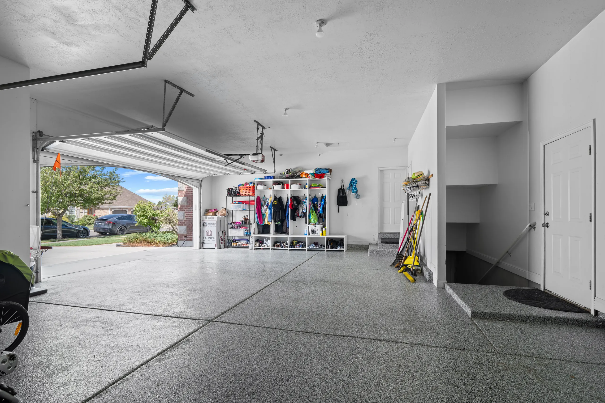 Three-car garage with an epoxy-flecked floor, built-in storage shelving and the door raised onto the driveway